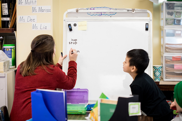 A teacher teaching a child using a white board